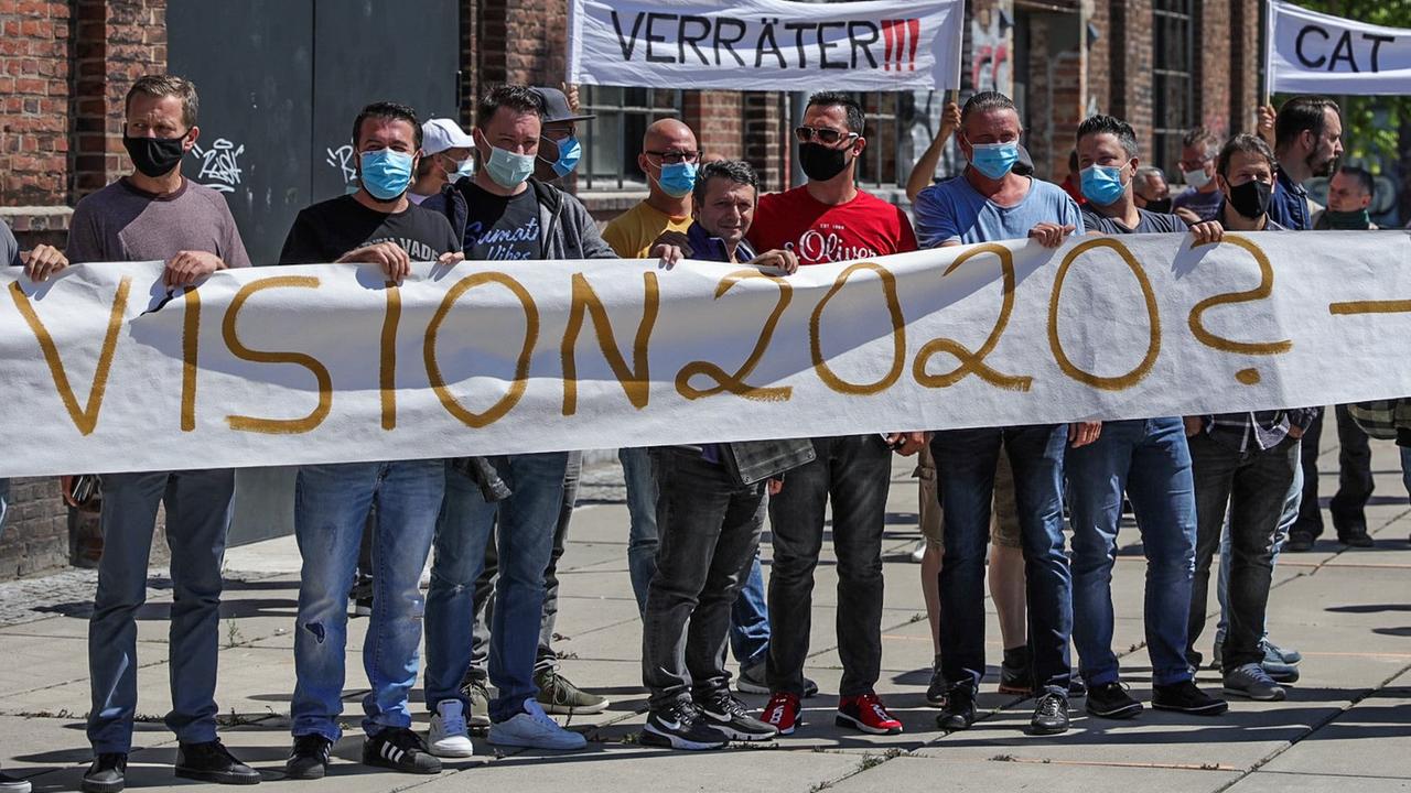 Mitarbeiter des Unternehmens Caterpillar protestieren gegen die Schließung des Standorts Dortmund mit einem Banner, auf dem "Vision 2020?" steht. Mitarbeiter des Unternehmens Caterpillar protestieren gegen die Schließung des Standorts Dortmund mit einem Banner, auf dem "Vision 2020?" steht.