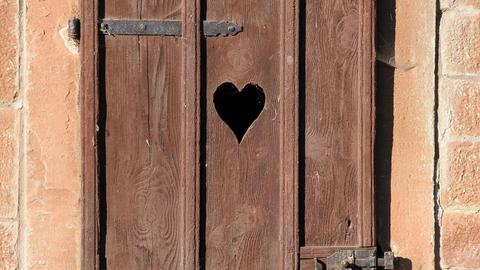 Die Tür eines mit einem Herz verzierten Toilettenhäuschens auf einem Bauernhof in Hessen.