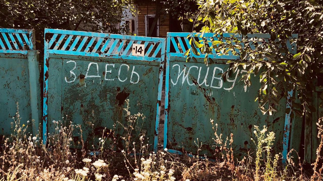 In dem Dorf Optina in der Pufferzone in der Ostukraine steht auf einem Tor: "Hier wohnt jemand."