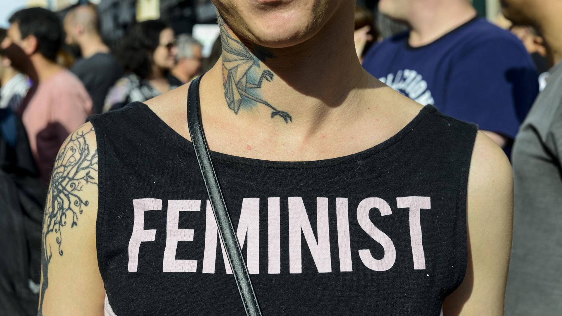 Eine junge Frau trägt ein T-Shirt mit der Aufschriftin "Feministin"