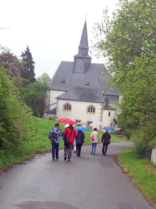 Besuchergruppe des "Eckweilerer Sommers", ein Kulturprogramm in Rheinland-Pfalz, auf dem Weg zur Heilig-Kreuz-Kirche im Hunsrück.