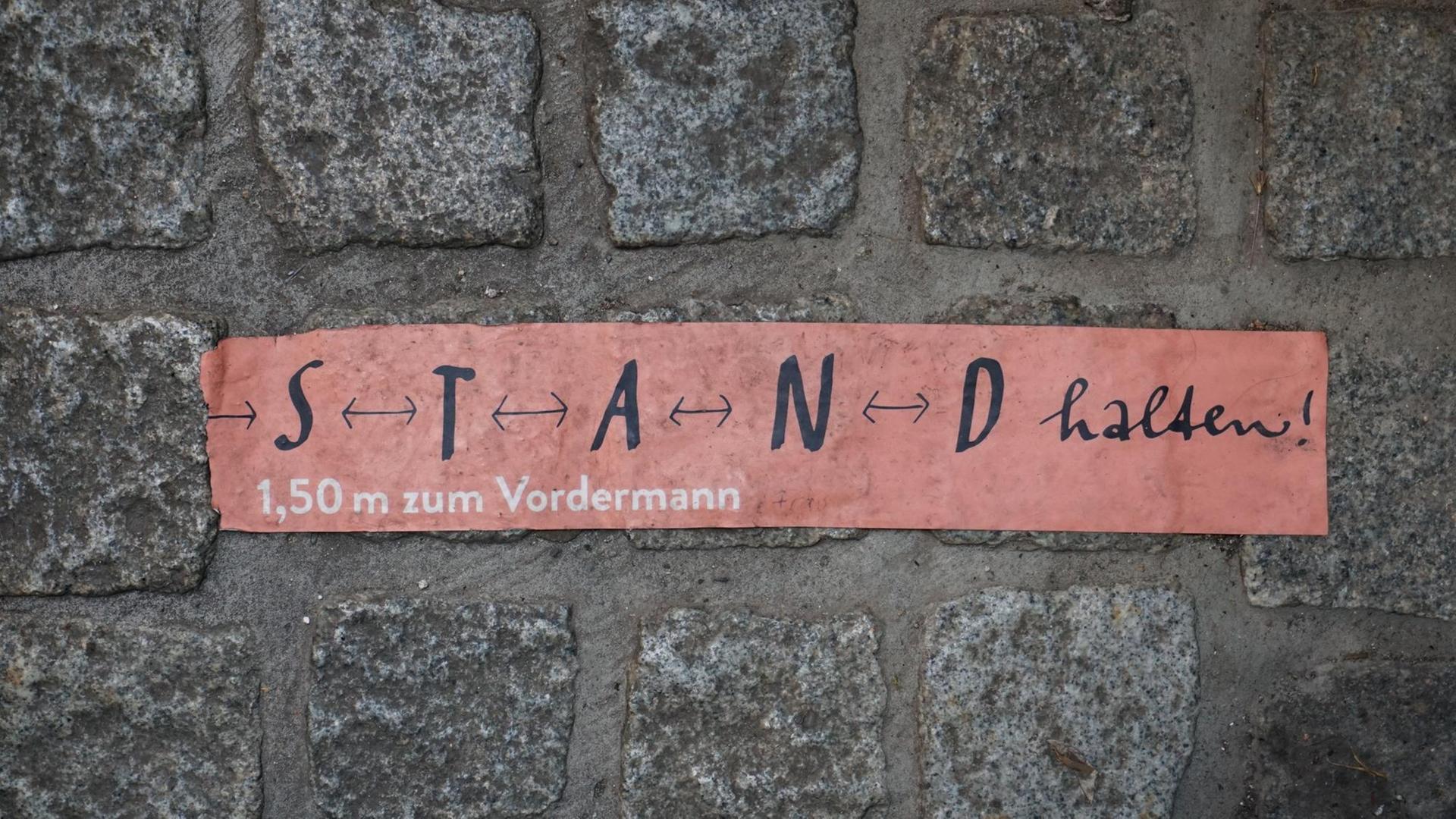 Aufkleber mit den Worten „S T A N D halten“ auf Kopfsteinpflaster in Erfurt.