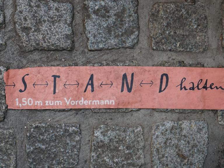 Aufkleber mit den Worten „S T A N D halten“ auf Kopfsteinpflaster in Erfurt.