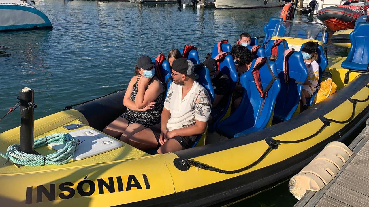 In einem Boot in einem Hafen sitzen wenige Touristen.