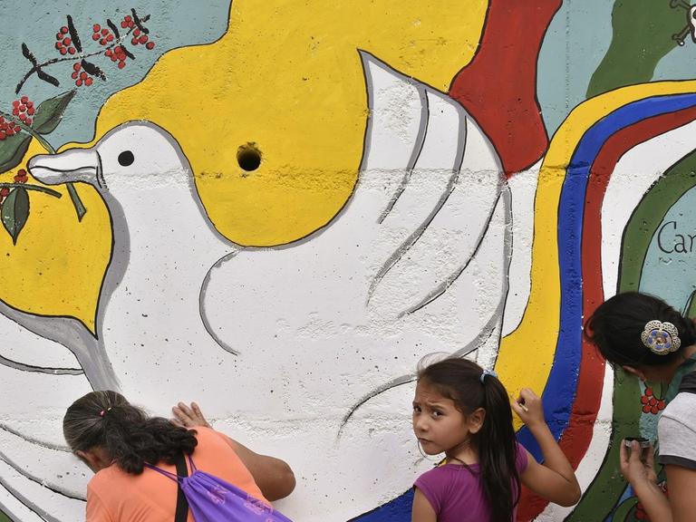 Frauen und Kinder malen ein Wandbild mit einer Taube an der Straße nach Planadas in Kolumbien.