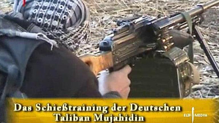 Ein Video zeigt einen Mann mit Turban, der liegend ein Maschinengewehr mit Ständer in der Hand hält und zielt. Ein eingeblendeter Schriftzug sagt "Das Schießtraining der Deutschen Taliban Mujahedin". Ein Video zeigt einen Mann mit Turban, der liegend ein Maschinengewehr mit Ständer in der Hand hält und zielt. Ein eingeblendeter Schriftzug sagt "Das Schießtraining der Deutschen Taliban Mujahedin".
