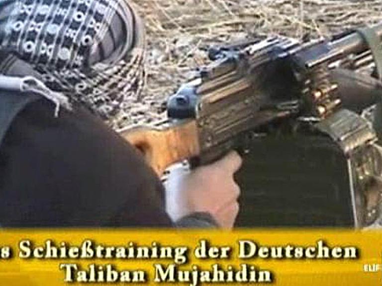 Ein Video zeigt einen Mann mit Turban, der liegend ein Maschinengewehr mit Ständer in der Hand hält und zielt. Ein eingeblendeter Schriftzug sagt "Das Schießtraining der Deutschen Taliban Mujahedin".