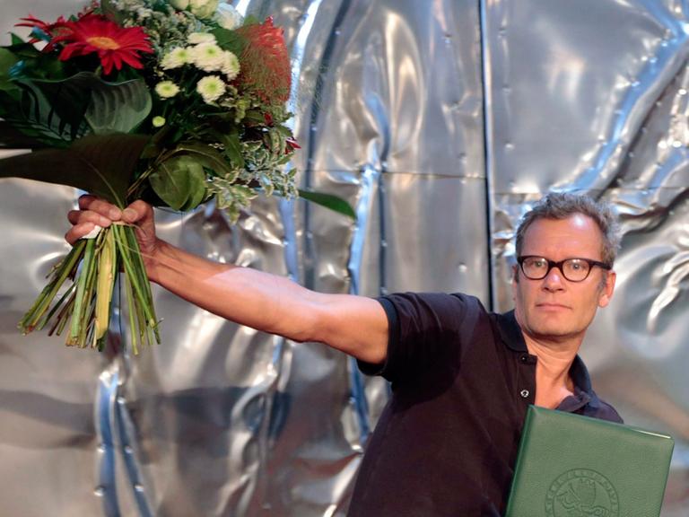 Der deutsche Schriftsteller Tex Rubinowitz, Gewinner des Ingeborg-Bachmann-Preises 2014, mit Blumenstrauß bei der Preisverleihung der 38. Tage der deutschsprachigen Literatur in Klagenfurt.