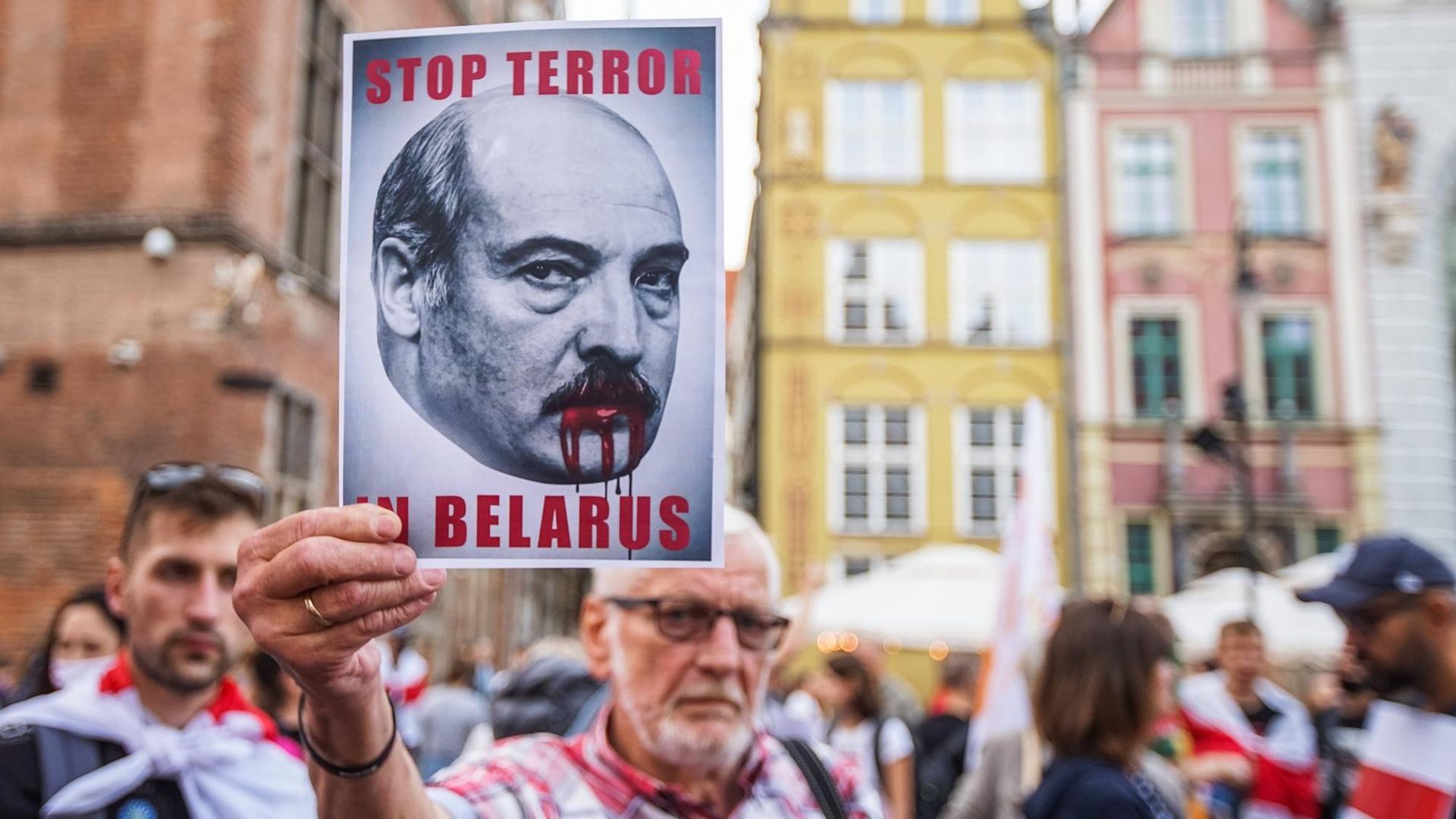 "Solidarity with Belarus March" in Gdansk. Ein Mann hält ein "Stop Terror in Belarus" Schild in die Höhe, 2021.