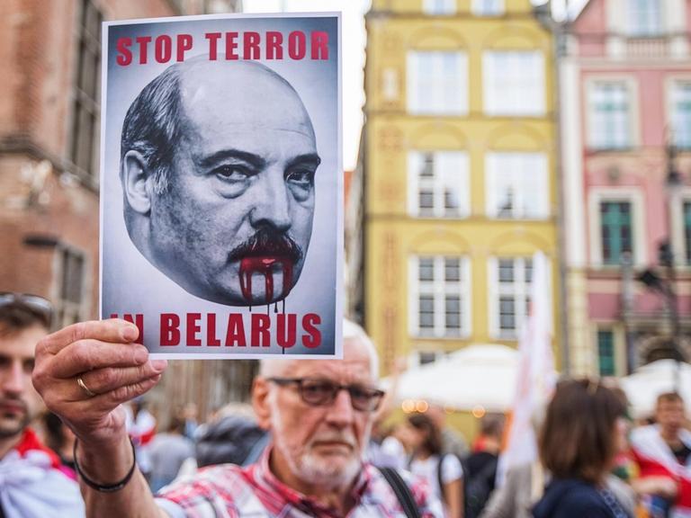 "Solidarity with Belarus March" in Gdansk. Ein Mann hält ein "Stop Terror in Belarus" Schild in die Höhe, 2021.