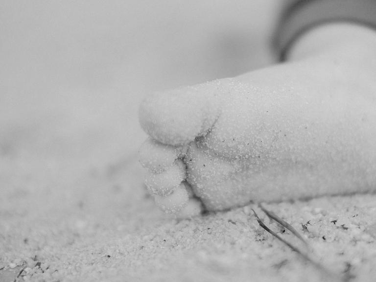 Der Fuß eines Kindes im Sand
