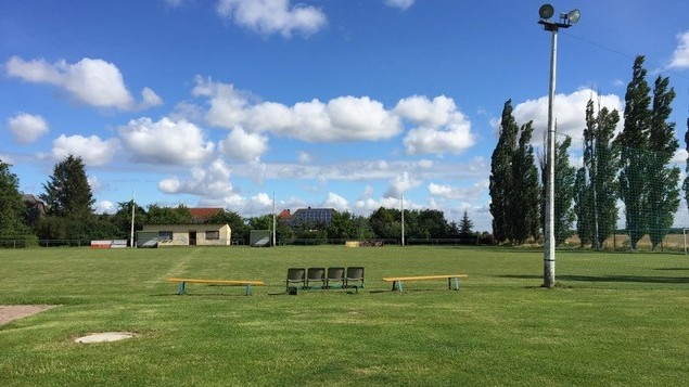 Ein leerer Fußballplatz unter strahlend blauem Himmel.