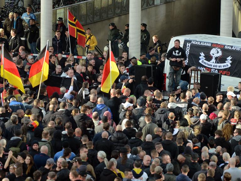 Demonstranten stehen am 26.10.2014 in Köln vor einem Fahrzeug mit einem Transparent der als gewaltbereit bekannten Gruppe "Hooligans gegen Salafisten".
