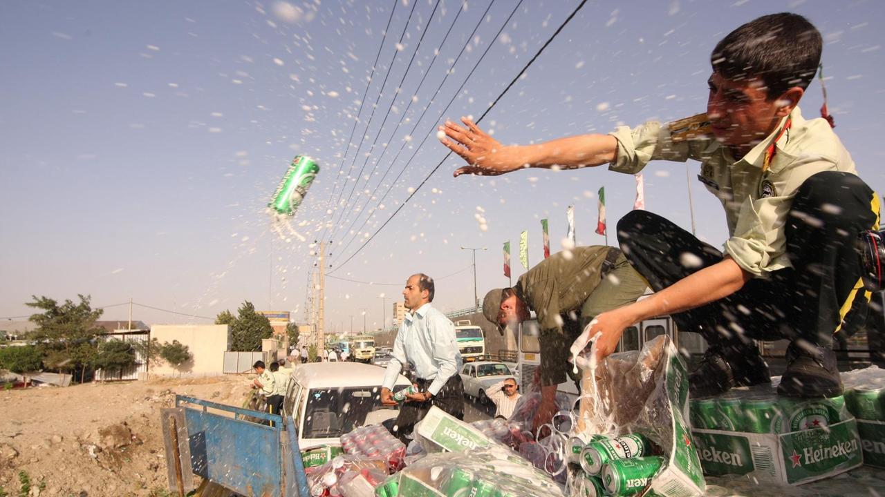 Iranische Polizisten gießen beschlagnahmte Bierdosen aus.