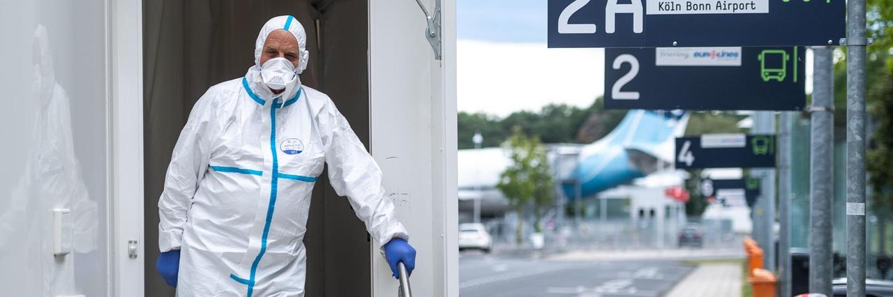 Ein Mitarbeiter des Corona-Testzentrum am Flughafen Köln/Bonn steht im Eingang des Testzentrums.