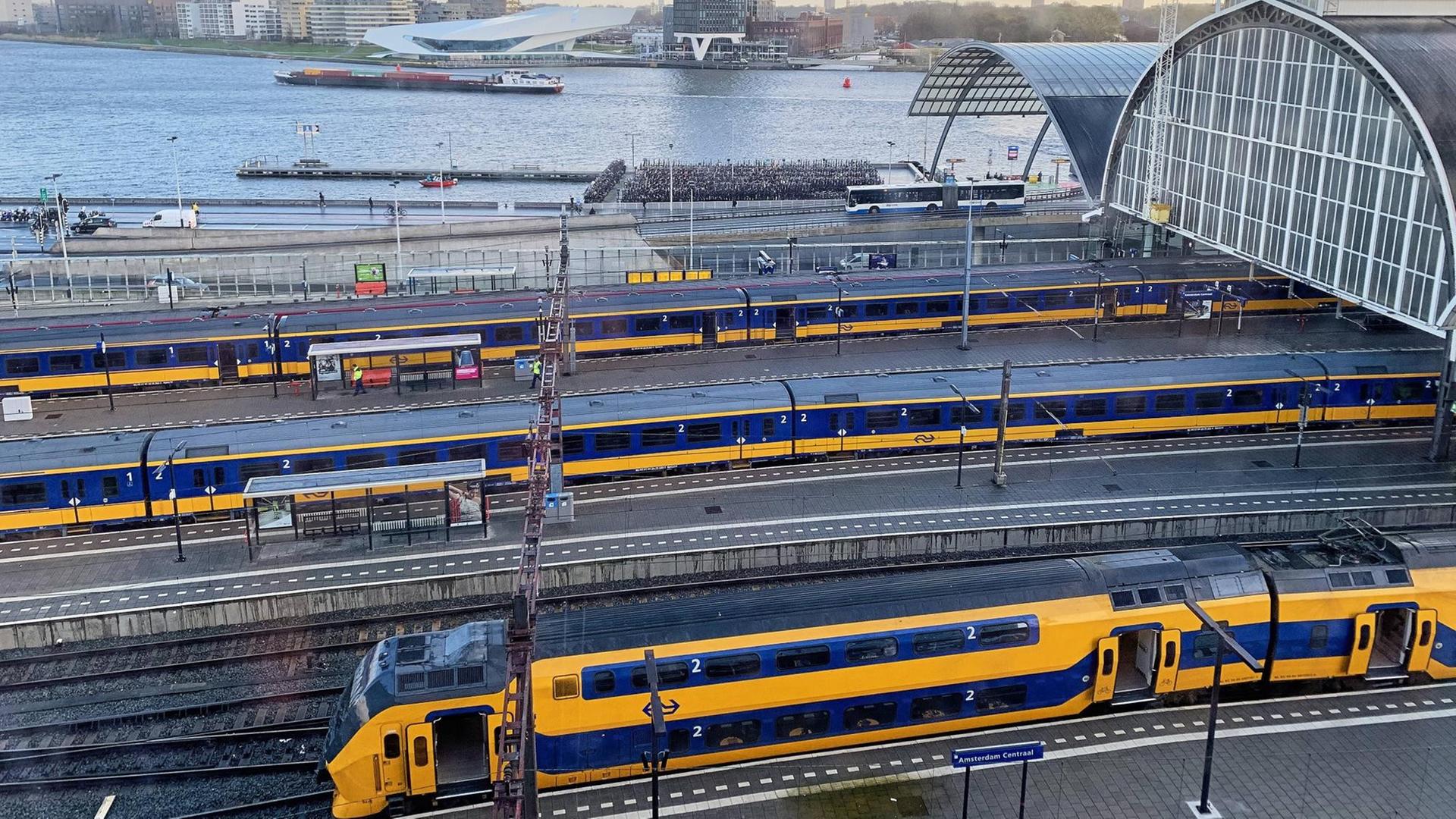 Zu sehen sind Doppelstockzüge der Niederländischen Eisenbahn in einem Bahnhof.
