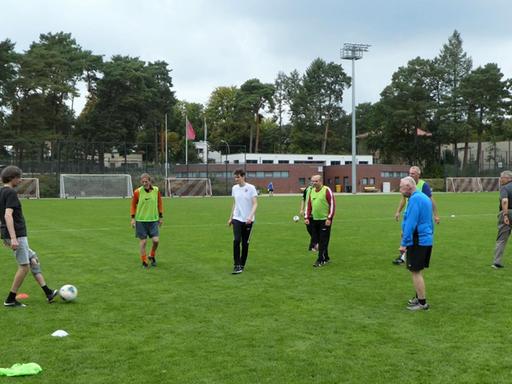 Ältere Männer spielen auf einem Fußballfeld Fußball.