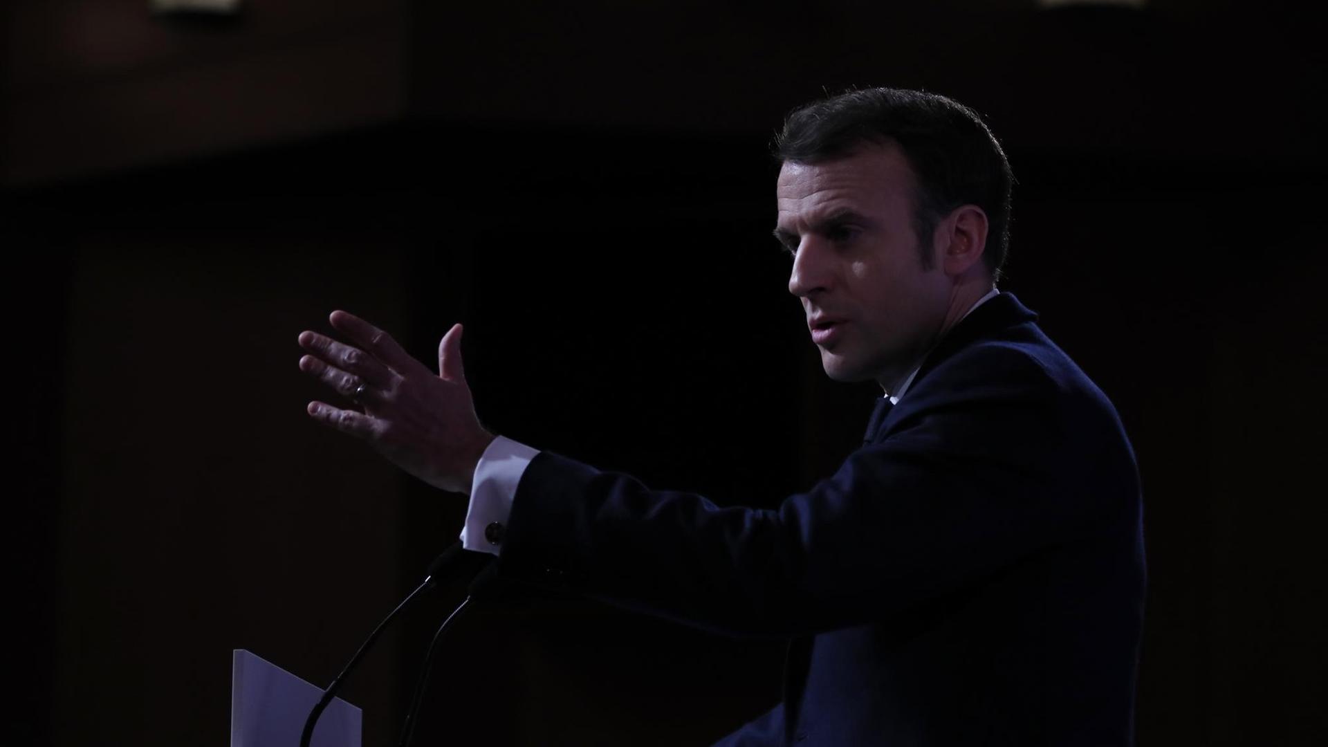Frankreichs Präsident Macron ist während einer Rede von der Seite zu sehen. Er spricht mit seinen Händen gestikulierend in Mikrofone.