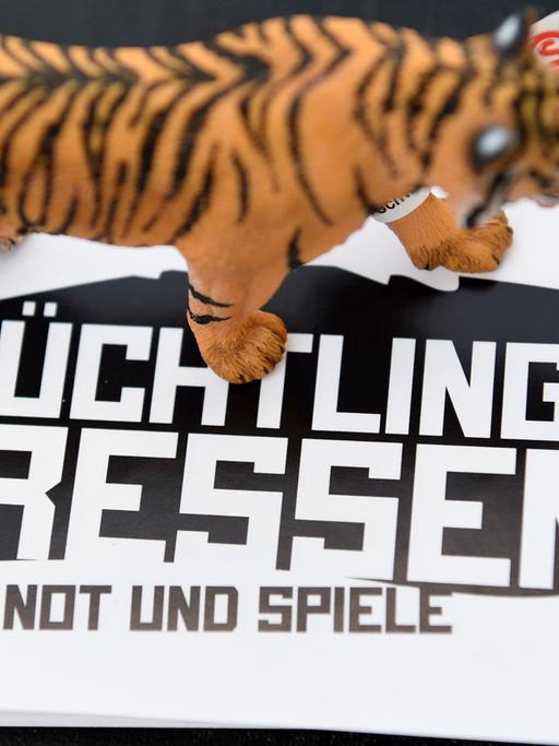 Ein schwarz-weißer Aufkleber mit der Aufschrift "Flüchtlinge fressen - Not und Spiele", auf dem eine Tigerfigur steht.
