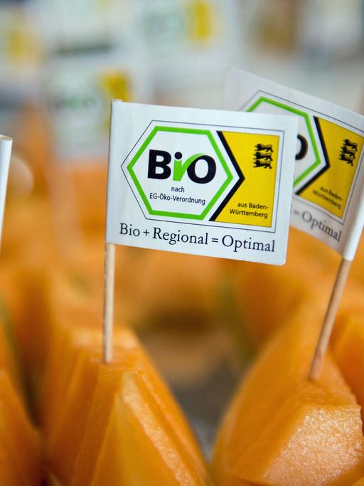 Kleine Fähnchen mit der Aufschrift "Bio+Regional=Optimal" stecken in Filderstadt im Bioland-Gemüsehof Hörz in Stücken von Hokkaidokürbissen.