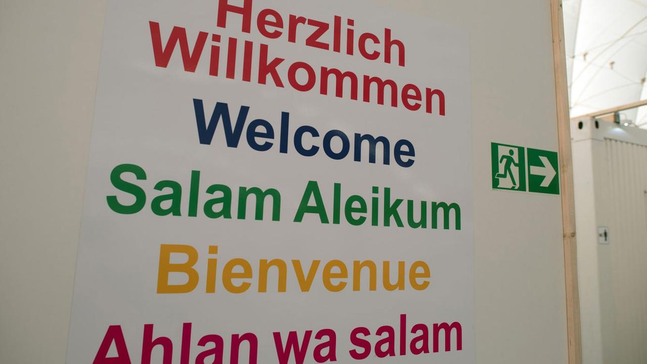 «Herzlich Willkommen» steht am 27.10.2015 in verschiedenen Sprachen auf einem Plakat in Düsseldorf (Nordrhein-Westfalen) in einer Traglufthalle. Rund 300 Flüchtlinge sollen hier winterfest untergebracht werden.  