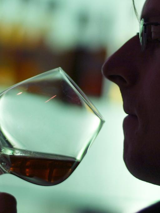 Ein Mann riecht an einem Glas Cognac in einer Hotelbar in München.