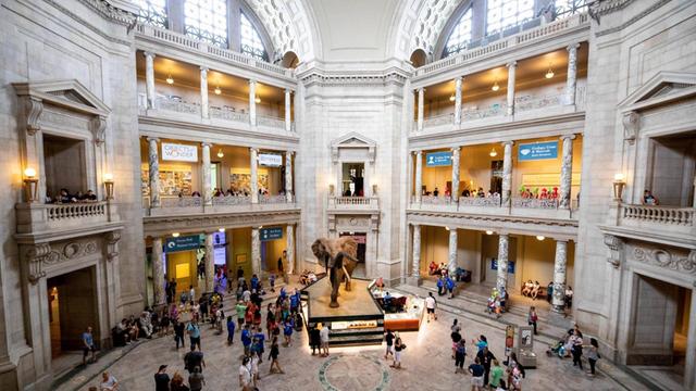Ein großer Saal in einem Museum. Es gibt mehrere Stockwerke und Gallerien. 