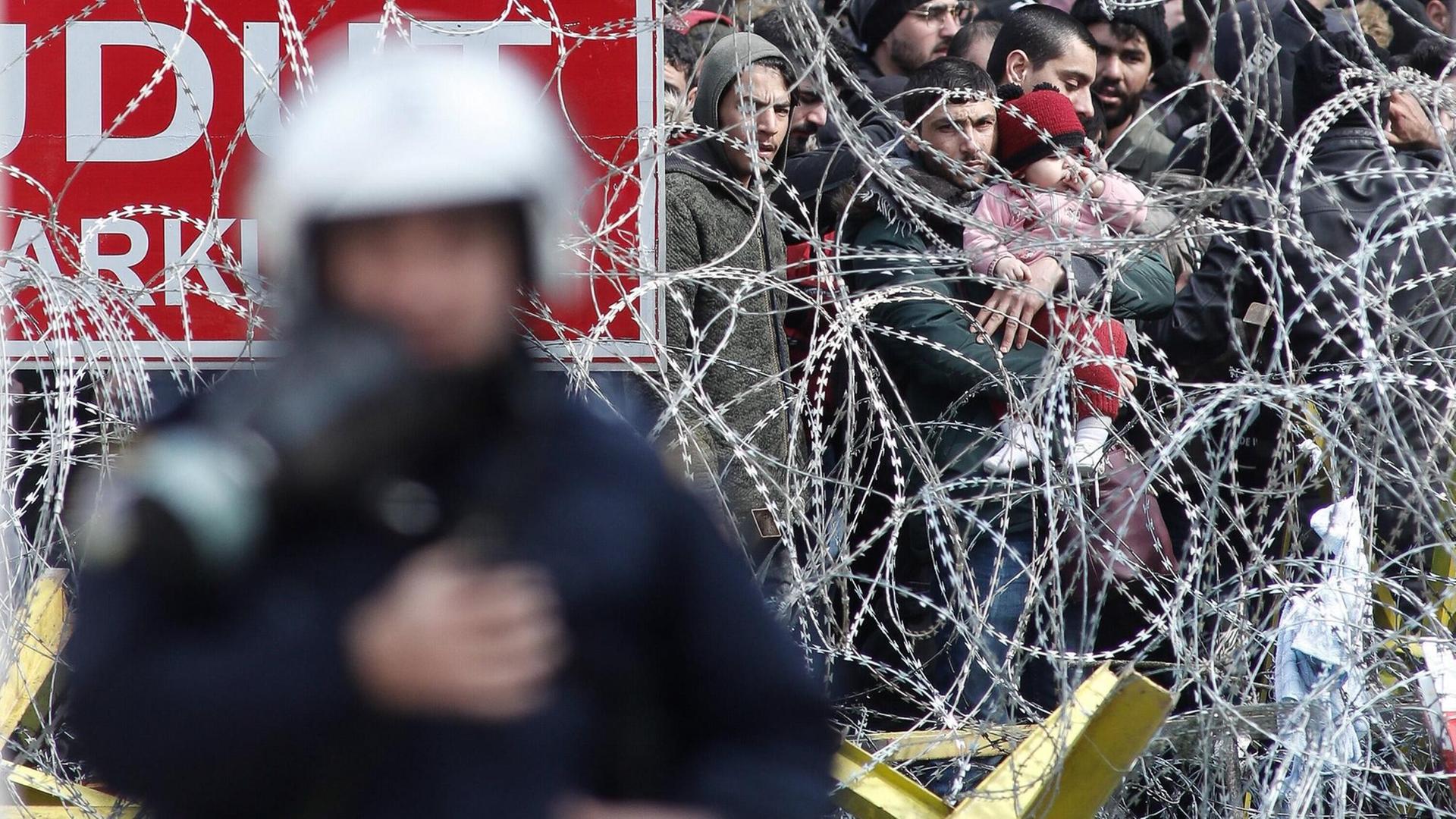 Flüchtlinge hinter einem Stacheldrahtzaun an der griechisch-türkischen Grenze