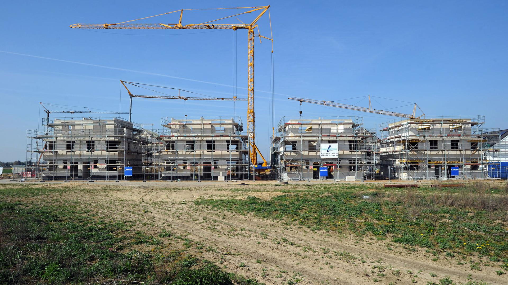 Ein Kran überragt im Neubaugebiet Widdersdorf-Süd in Köln (Nordrhein-Westfalen) im Bau befindliche Häuser. Auf etwa 1200 Baugrundstücken entstehen hier Ein- und Mehrfamilienhäuser.