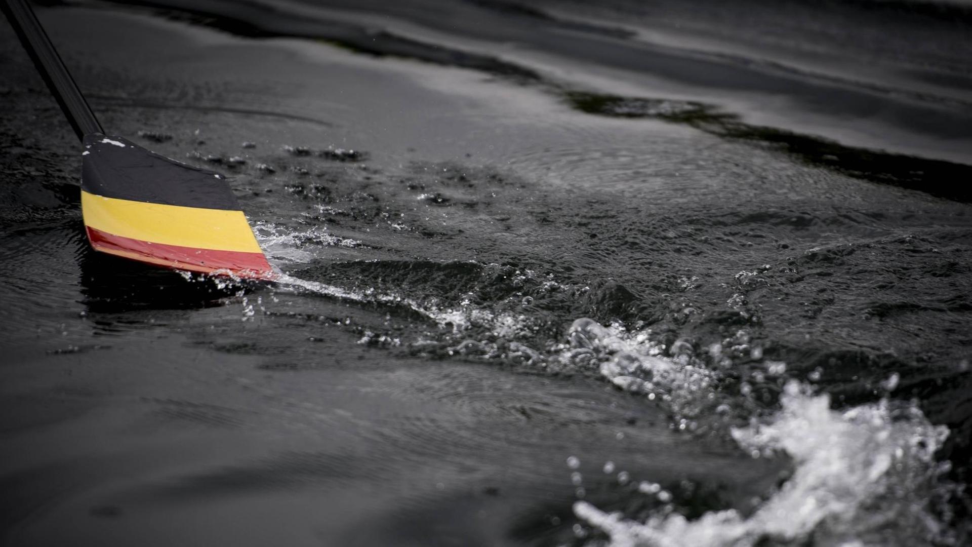 Eine belgische Flagge liegt am Boden inmitten von Wasser.