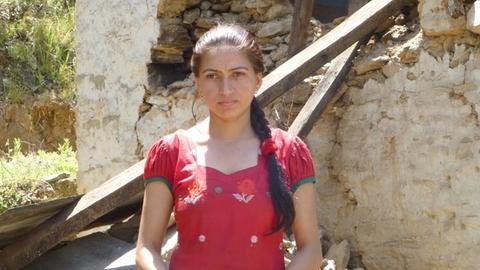 Sarita vor ihrem zerstörten Haus, für dessen Wiederaufbau nun das Geld benötigt wird, mit dem ihre Familie ihr Studium finanzierte.