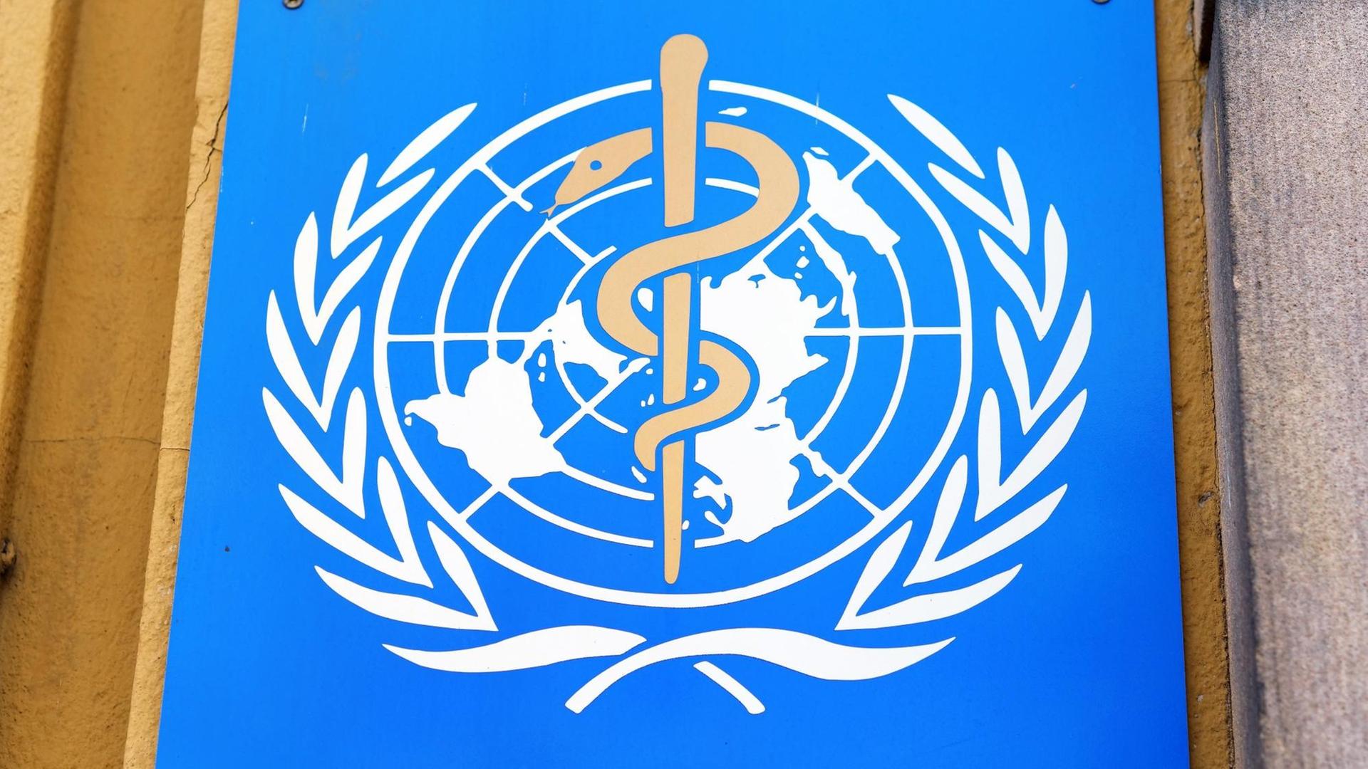 Das blau-weiße Logo der Weltgesundheitsorganisation hängt an einer Wand.