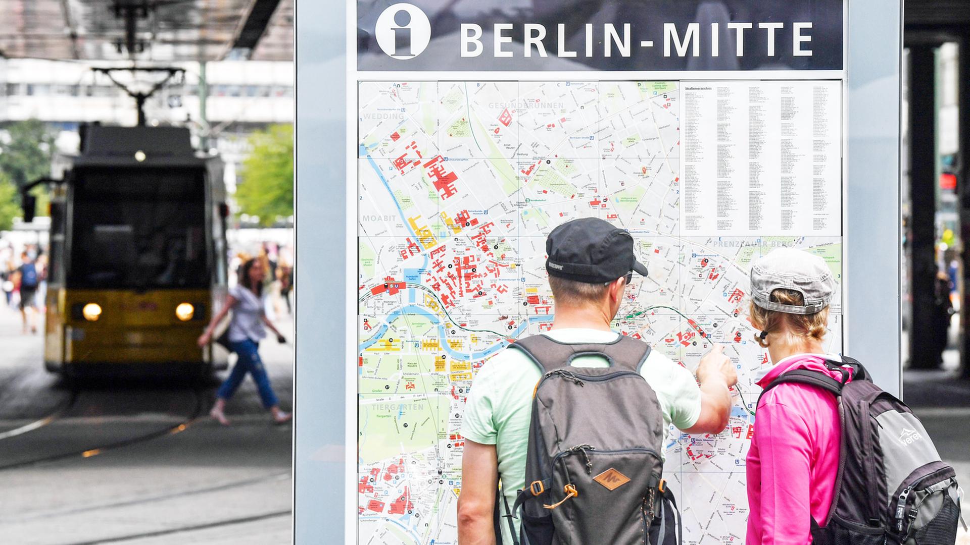Eine Straßenbahn passiert zwei Passanten an einem Stadtplan in Berlin-Mitte Eine Straßenbahn passiert zwei Passanten an einem Stadtplan in Berlin-Mitte