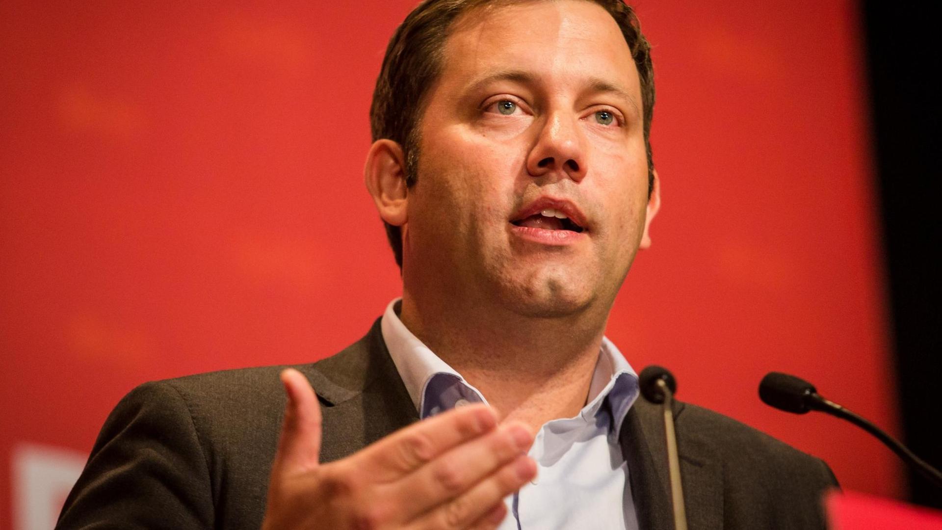 SPD-Generalsekretär Lars Klingbeil sprechend an einem Mikrophon vor rotem Hintergrund