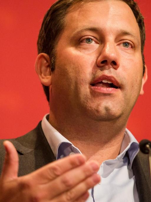 SPD-Generalsekretär Lars Klingbeil sprechend an einem Mikrophon vor rotem Hintergrund