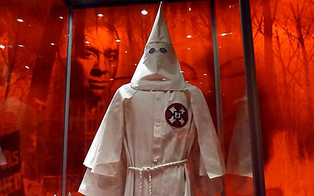Die Robe eines Ku-Klux-Klan-Mitglieds, dahinter das Gesicht eines Schwarzen in einer Ausstellung in Washington