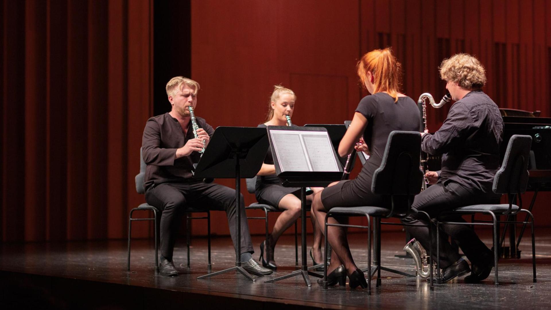 Die vier Klarinettisten spielen auf dem Konzertpodium.