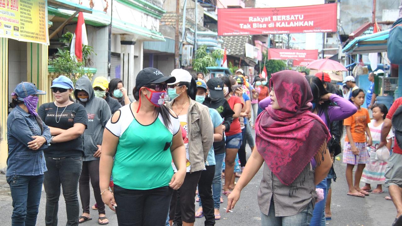 Im indonesischen Surabaya protestieren Prostituierte für den Erhalt ihres Rotlicht-Viertels. Sie stehen in Reih und Glied, viele von ihnen verstecken ihr Gesicht hinter Atemmasken, Sonnenbrillen und unter Mützen. 