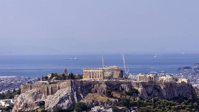 Sicht auf die Akropolis in der griechischen Hauptstadt Athen vom Hügel Lycabettus aus, im Hintergrund das Meer.