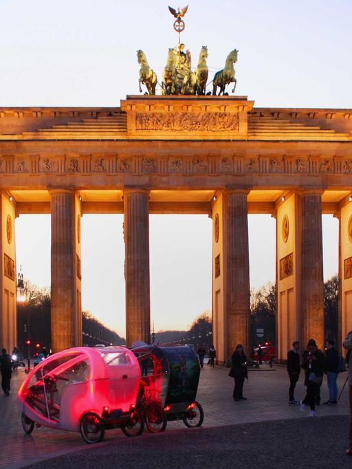 Touristen stehen am 15.02.2017 in Berlin abends am Brandenburger Tor und fotografieren.