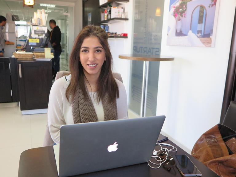 Die junge Start-up-Unternehmerin Laila Akel sitzt vor ihrem Laptop in einem Café.