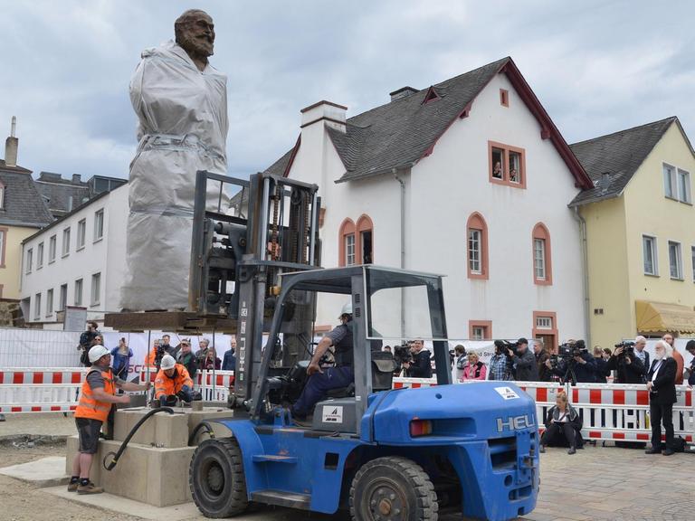 Die größtenteils mit einer Plane verdeckte 2,3 Tonnen schwere und 4,40 Meter große Karl-Marx-Statue des chinesischen Künstlers Wu Weishan wird in Trier aufgestellt.