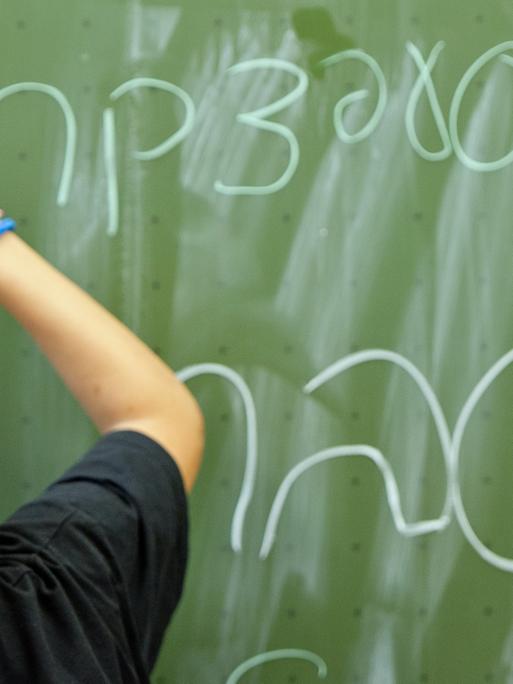 Ein Schüler der Talmud Tora Schule in Hamburg schreibt das Alphabet auf hebräisch an die Tafel. Unten steht das Wort "lernen".
