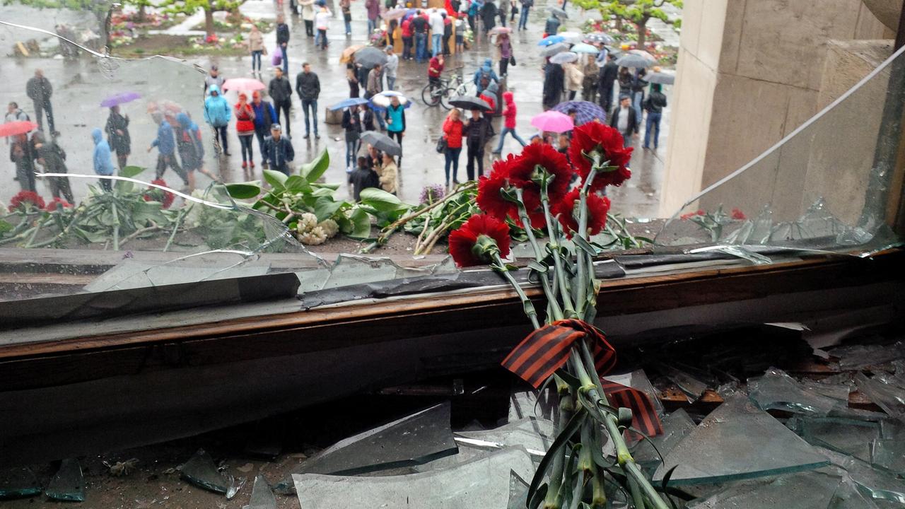 Rote Nelken liegen einem zerstörten Fenster des Gewerkschaftshaus in Odessa