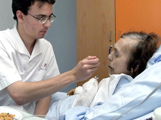 Zivildienstleistender reicht alter Frau eine Mahlzeit. Zivildienstleistender reicht alter Frau eine Mahlzeit.