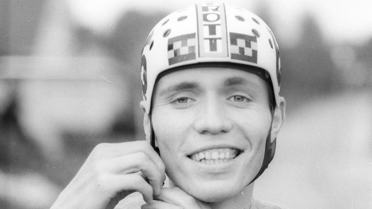 Schwarz-Weiß-Porträt des Amateur-Radrennfahrers Wilfried Trott, auf dem dieser den von seinem Vater entwickelten Fahrradhelm trägt.
