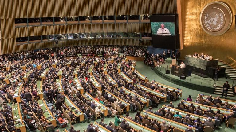 Ein großer Raum mit vielen Zuschauerreihen und einem Rednerpult - der Saal der Vollversammlung der Vereinten Nationen Ein großer Raum mit vielen Zuschauerreihen und einem Rednerpult - der Saal der Vollversammlung der Vereinten Nationen