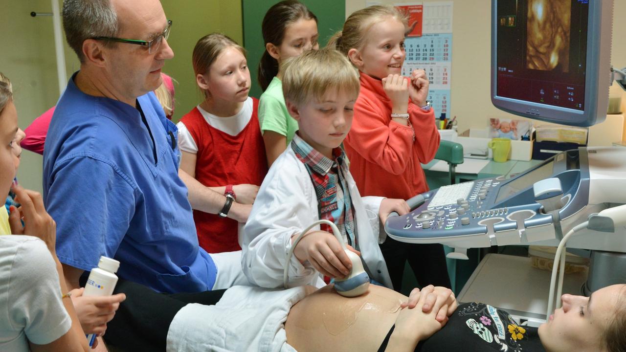Schüler begleiten den Chefarzt eines Krankenhauses in Halle (Saale) bei der 3D-Ultraschall-Untersuchung einer schwangeren Frau.