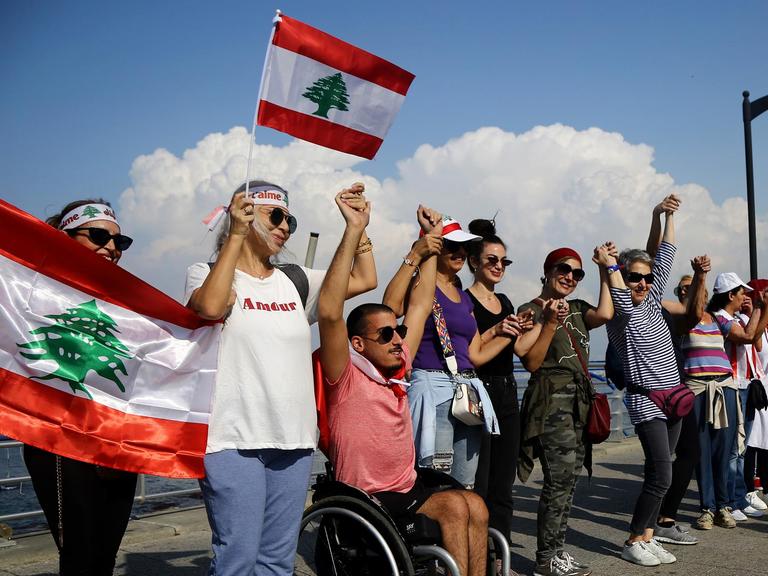 Libanesen halten libanesische Flaggen während sie eine Menschenkette als Zeichen nationaler Einheit bilden.