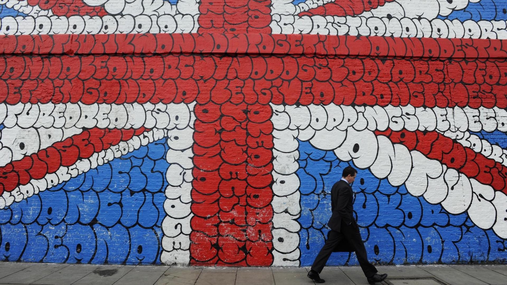 Ein Mann läuft an einem Grafitti, das die britische Flagge zeigt, vorbei.